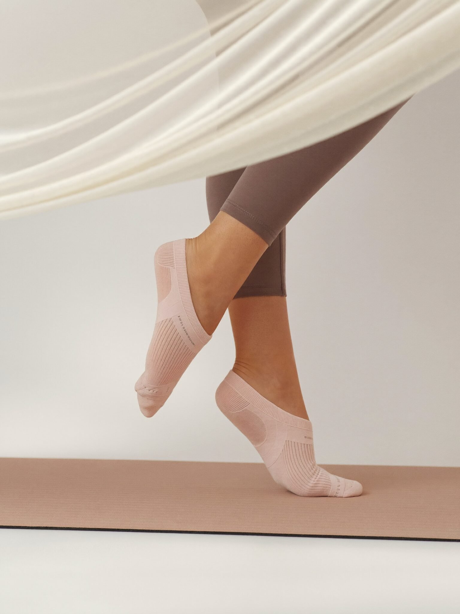 Blush grip socks on tiptoe on a pink Pilates mat